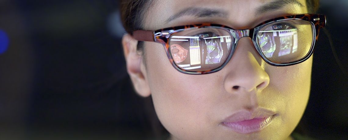 Woman with glasses looking at a monitor