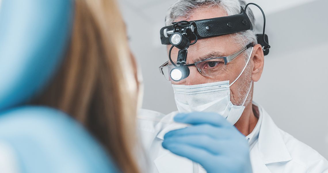 ENT working with a patient, and wearing a head lamp