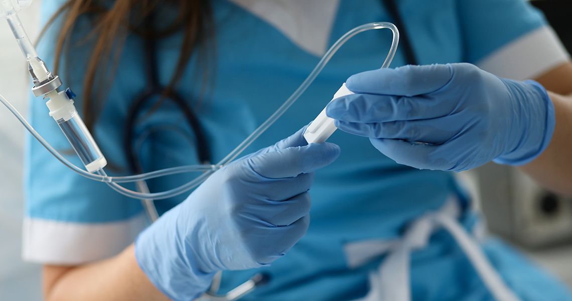 Female nurse hand in blue protective gloves hold dropper