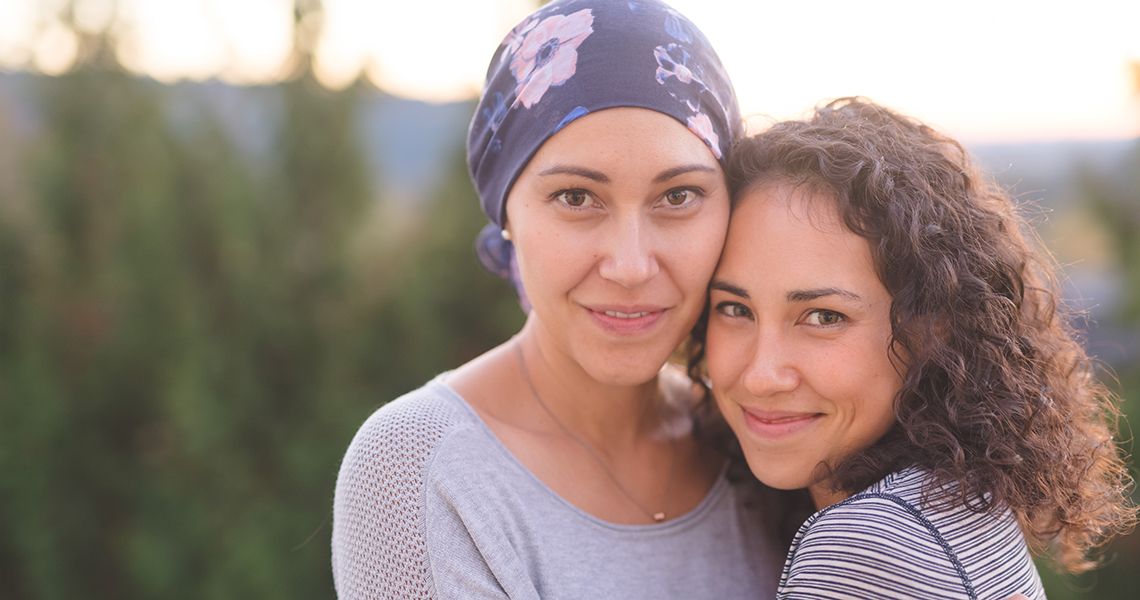two sisters hugging, one is wearing a scar on her head