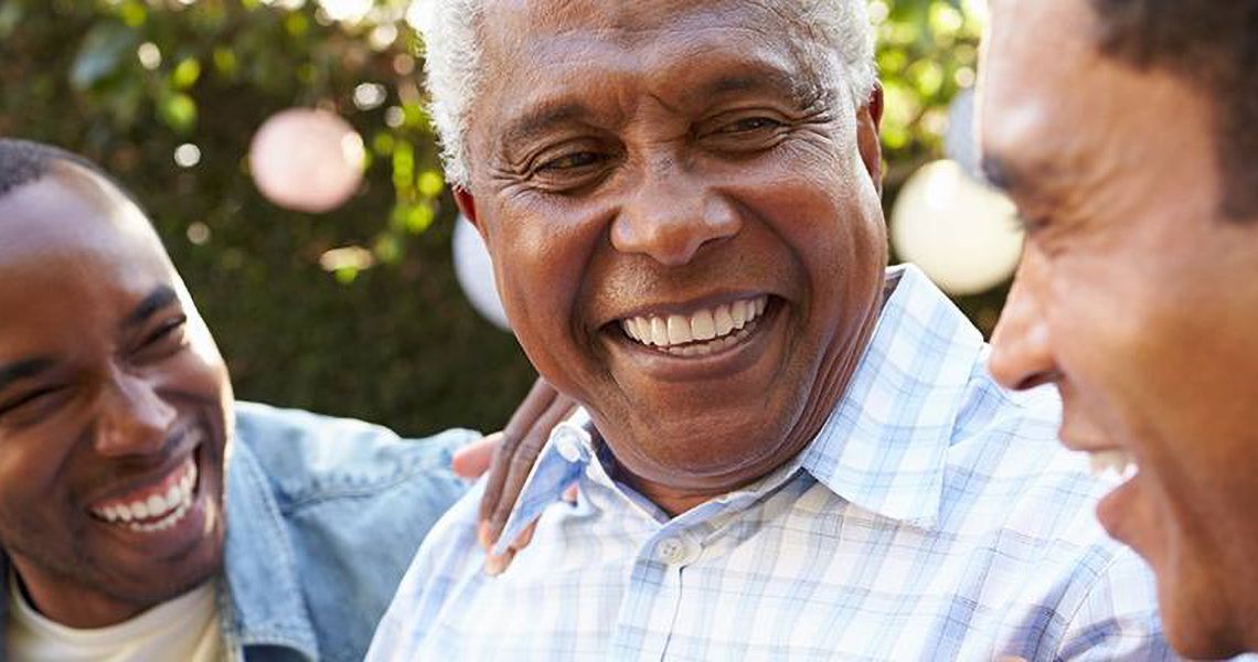 Older man laughing with two younger sons
