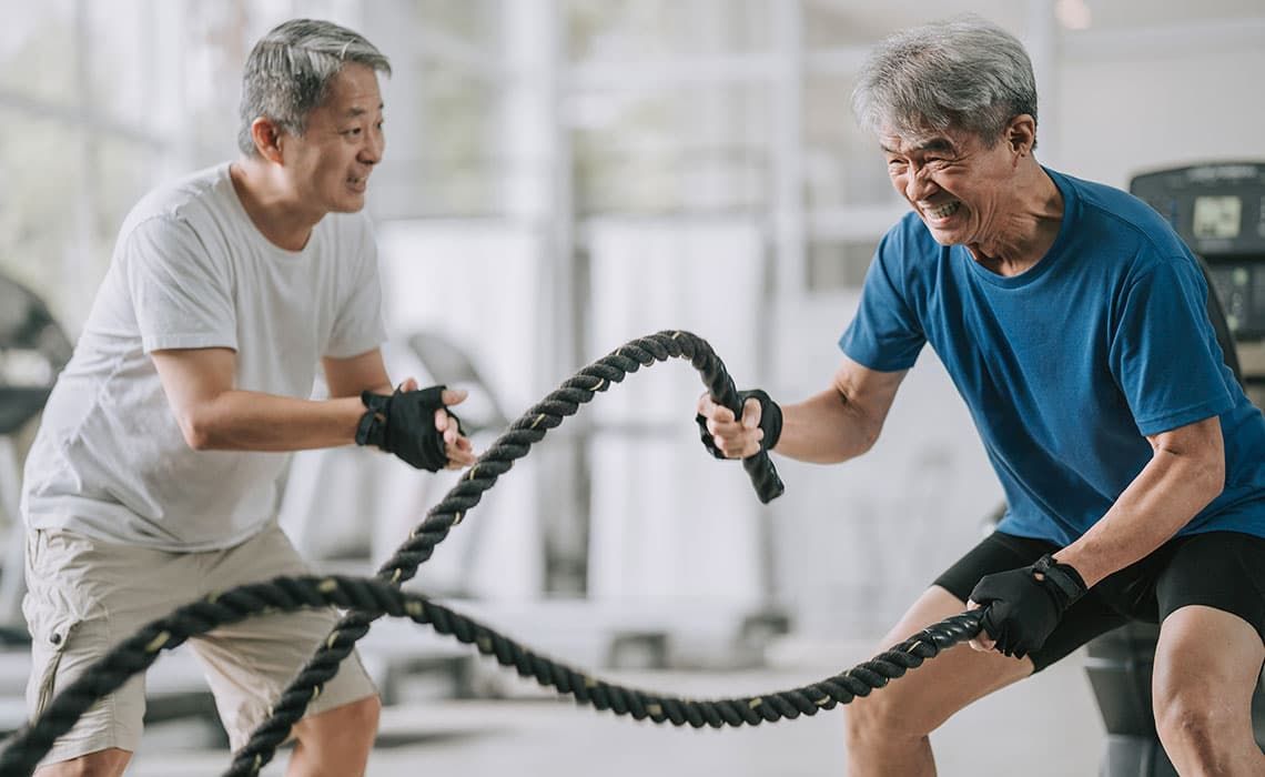A personal trainer encouraging a man in his HIIT rope swing exercise