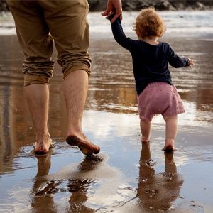 Father walking with his toddler in shallow water
