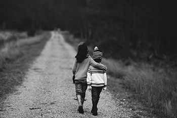 two kids walking, one with arm around the other