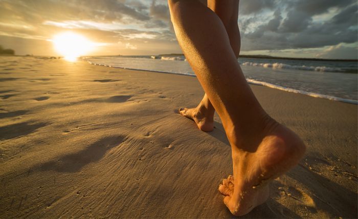 Legs from the ankle-down walking on a beach at sunset