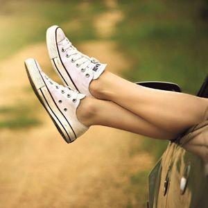 Legs with white shoes hanging out of a car window