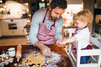 Father cooking with a child, breaking eggs