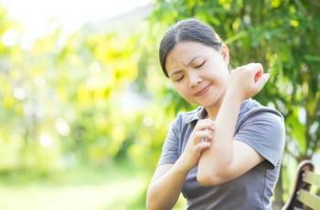 Woman outside scratching her arm